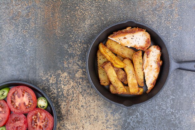 Roasted chicken and potatoes on pan with vegetable plate. High quality photo