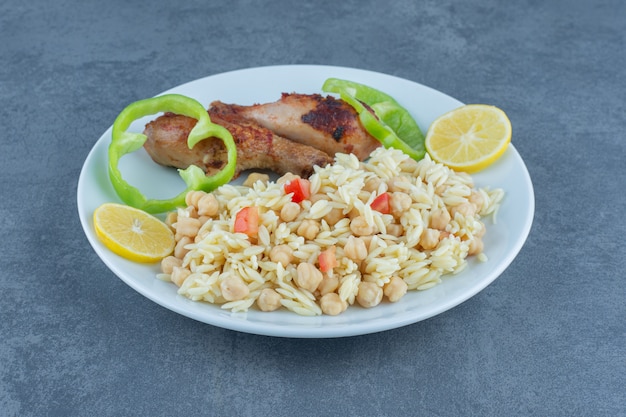 Roasted chicken and rice with chickpeas on white plate. 