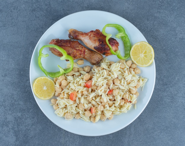 Roasted chicken and rice with chickpeas on white plate. 