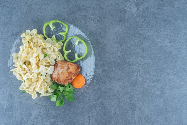 Roasted chicken and tasty pasta on glass plate.