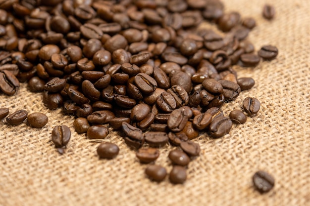 Free photo roasted coffee beans isolated on burlap fabric background with free space for text