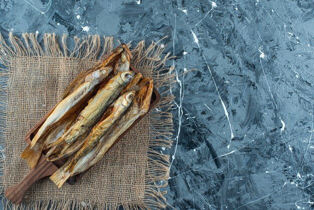 Roasted fish on a board on the texture , on the blue table. 