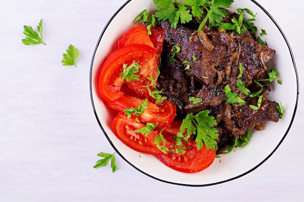 Roasted or grilled beef liver with onion and tomatoes salad