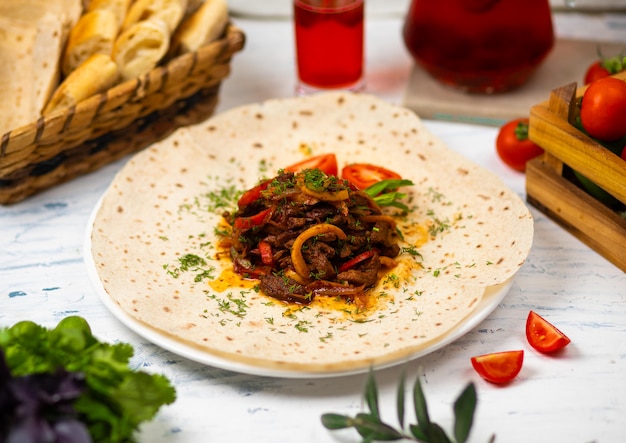 Roasted meat and vegetables with herbs on a white plate with bread vegetables and glass of wine