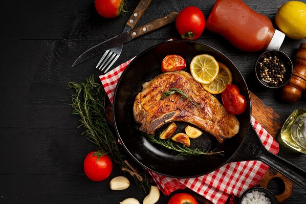 Roasted pork steak on the dark wooden surface.