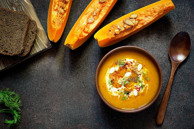 Free Photo roasted pumpkin and carrot soup with cream, seeds and fresh green in ceramic bowl. top view