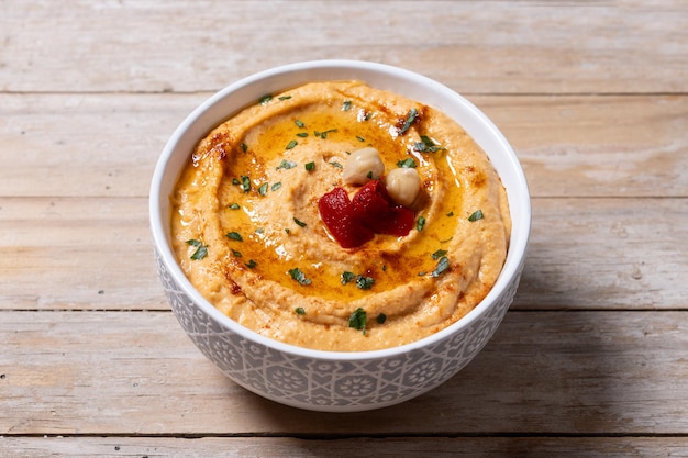 Free photo roasted red pepper hummus in white bowl on wooden table