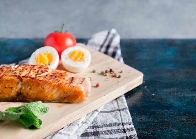 Free photo roasted salmon with boiled egg on blue table