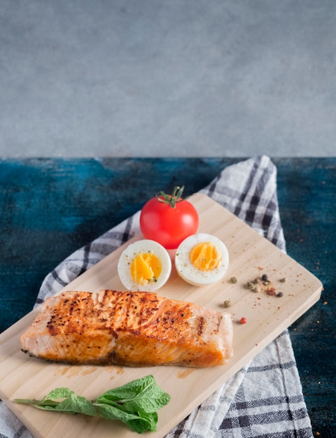 Free photo roasted salmon with boiled egg on wooden board