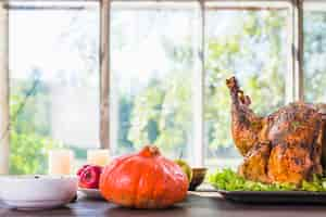 Free photo roasted turkey with orange pumpkin on table