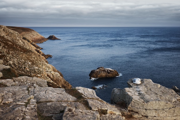 Rock formation island near coastal rocks under nimbus clouds