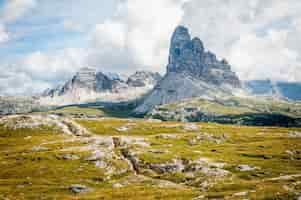 Free photo rock formation on wide field grass under cloudy blue sky during daytime