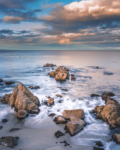 Free Photo rock formations in the sea under the white clouds