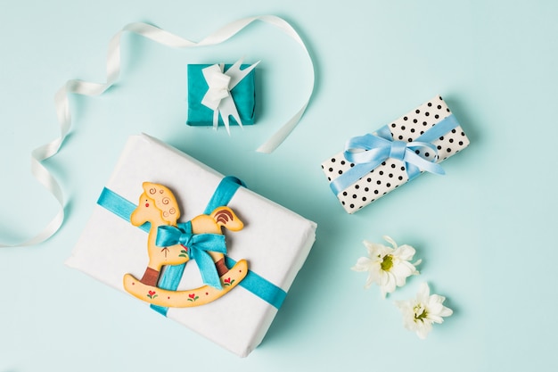 Rocking horse toy with gift boxes; flowers and ribbon over blue backdrop