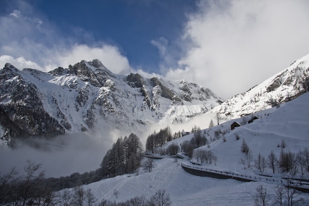 Rocky mountain covered with snow and fog during winter with a blue sky in the