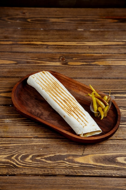 Free photo roll in pita bread and hot pepper on a wooden tray