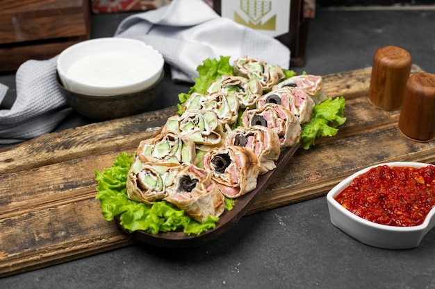 Roll salad in lavash bread on a lettuce leaf served with tomato paste