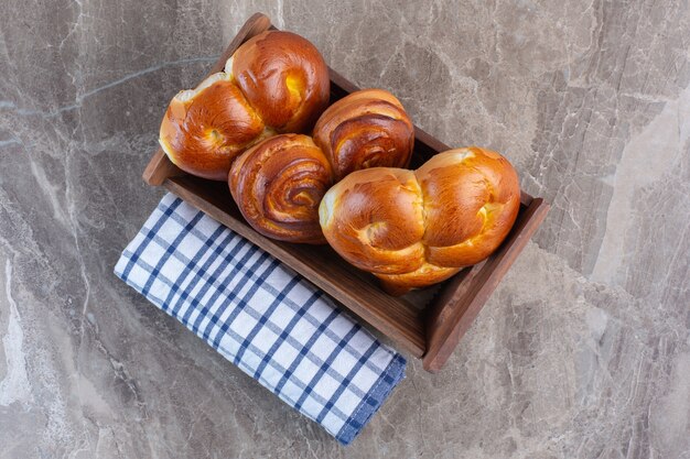 Roll of tablecloth and a basket of sweet buns on marble.