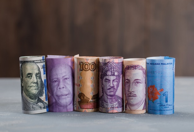 rolled banknotes on plaster and wooden table .