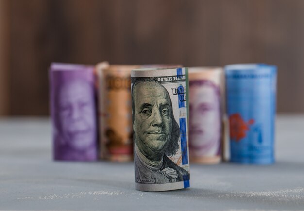 rolled banknotes on plaster and wooden table .