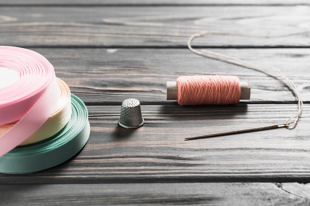 Free Photo rolled colorful ribbons and sewing item on wooden table