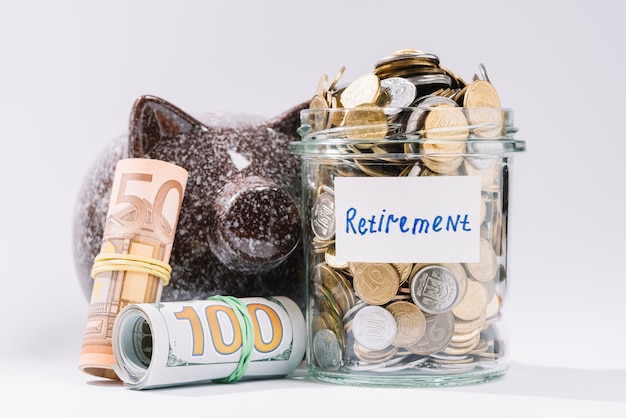 Free photo rolled up banknotes; piggybank and retirement container full of coins on white backdrop