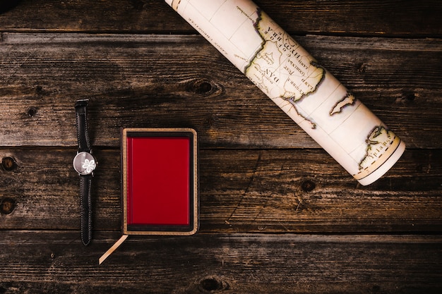 Free Photo rolled up map, diary and wrist watch on wooden table