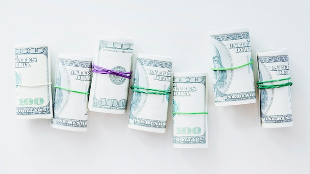 Free photo rolled up one hundred us dollar bills tied with rubber on white background