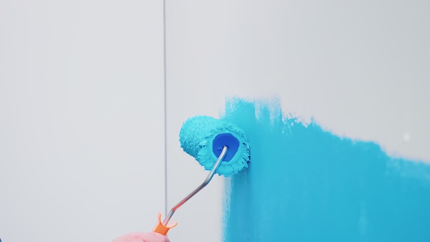 Free photo roller brush on wall with blue paint. apartment redecoration and home construction while renovating and improving. repair and decorating.