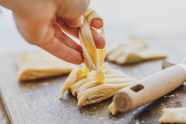 Free photo rolling fresh homemade pasta with flour on wooden board on table.