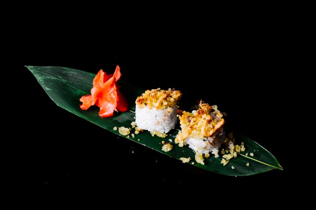 Rolls with crackers in the top on a green leaf with ginger in dark space.