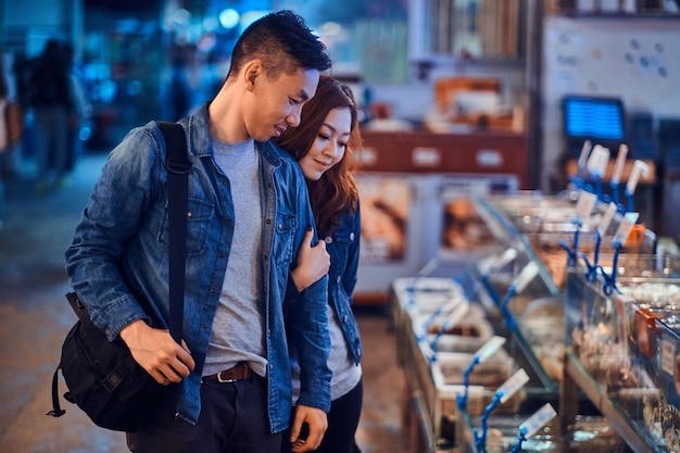 Romantic asian couple looking for something special at seafood chainese market. They are curious and joyful.