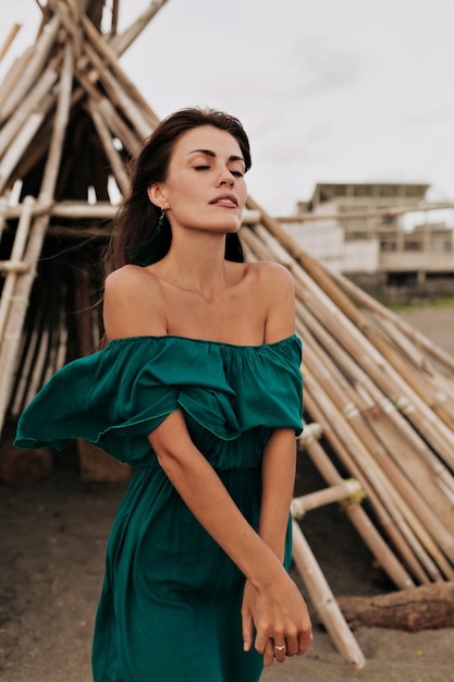 Free photo romantic beautiful woman wearing green summer dress with bare shoulders with closed eyes