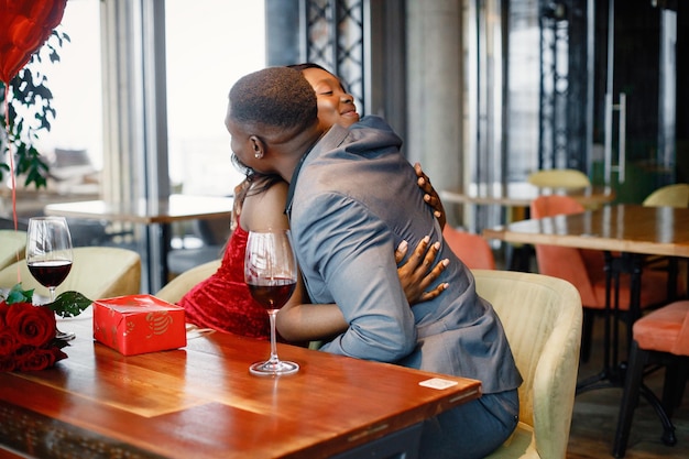 Free photo romantic black couple sitting at restaurant wearing elegant clothes