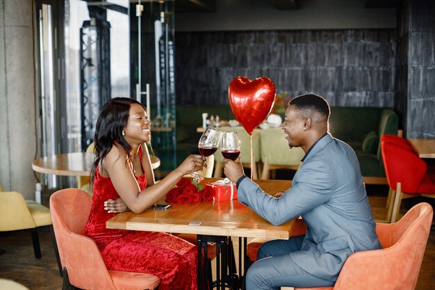 Romantic black couple sitting at restaurant wearing elegant clothes