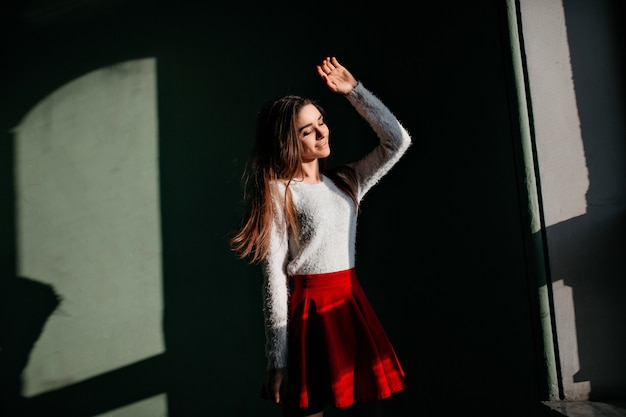 Romantic brown-haired lady enjoying sunlight while posing in the dark