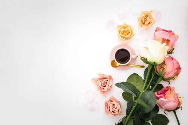 Romantic composition with roses, petals and pink cup of coffee with copy space