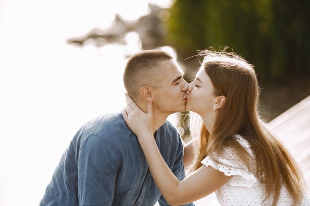 Romantic couple boyfriend and girlfriend kissing near the lake. Man and woman looking at each other and kissing