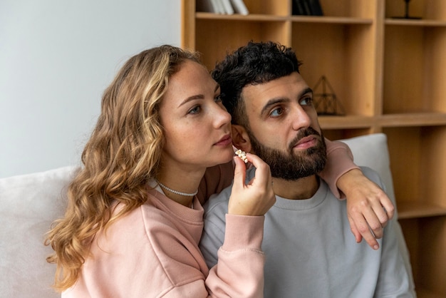 Romantic couple eating popcorn and watching movie at home