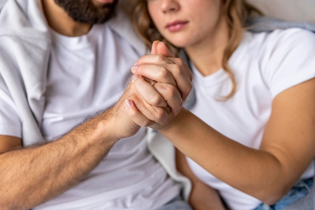 Free Photo romantic couple holding hands on the sofa at home