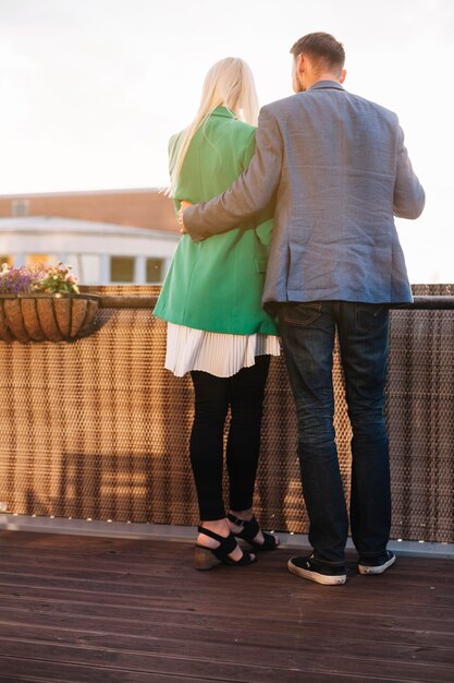 Romantic couple holding wine glasses standing in balcony looking at each other