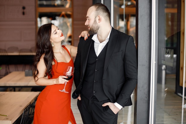 Free Photo romantic couple standing in restaurant on a date with glass of wine