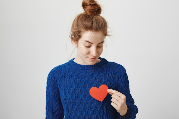 Free photo romantic cute redhead girl holding heart sign