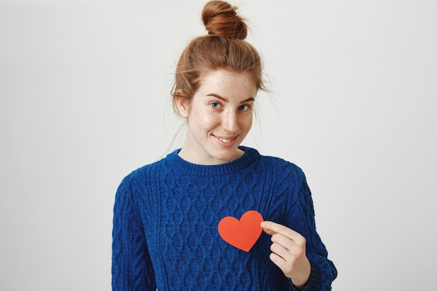 Free Photo romantic cute redhead girl holding heart sign