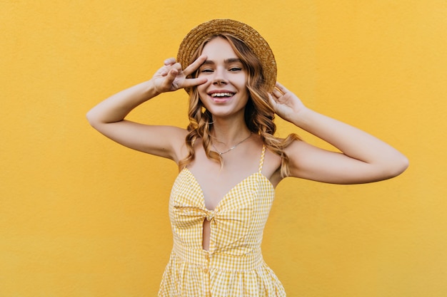 Free photo romantic fair-haired woman in checkered dress expressing happiness. indoor portrait of well-dressed girl smiling.