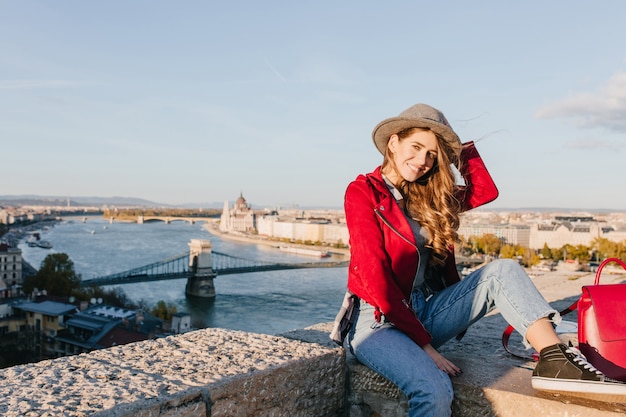 Free Photo romantic girl in black gumshoes sitting on roof and playing with brown hair