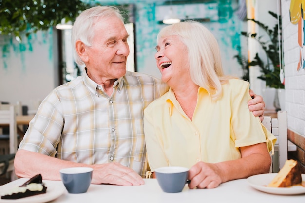 Romantic happy mature couple sitting in cafe and embracing