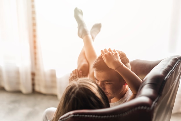 Romantic loving young couple lying on sofa near the window