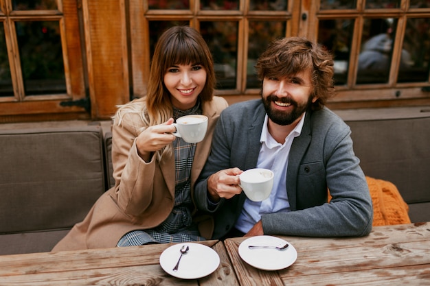 Romantic moments of elegant couple in love sitting in a cafe, drinking coffee, having a conversation and enjoying the time spend with each other.