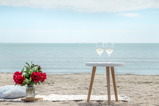 Free photo romantic picnic with flowers and glasses of champagne by the sea. the concept of a holiday.